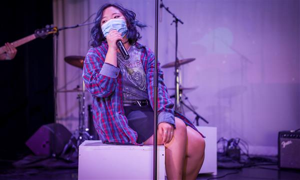 girl sits on box and sings
